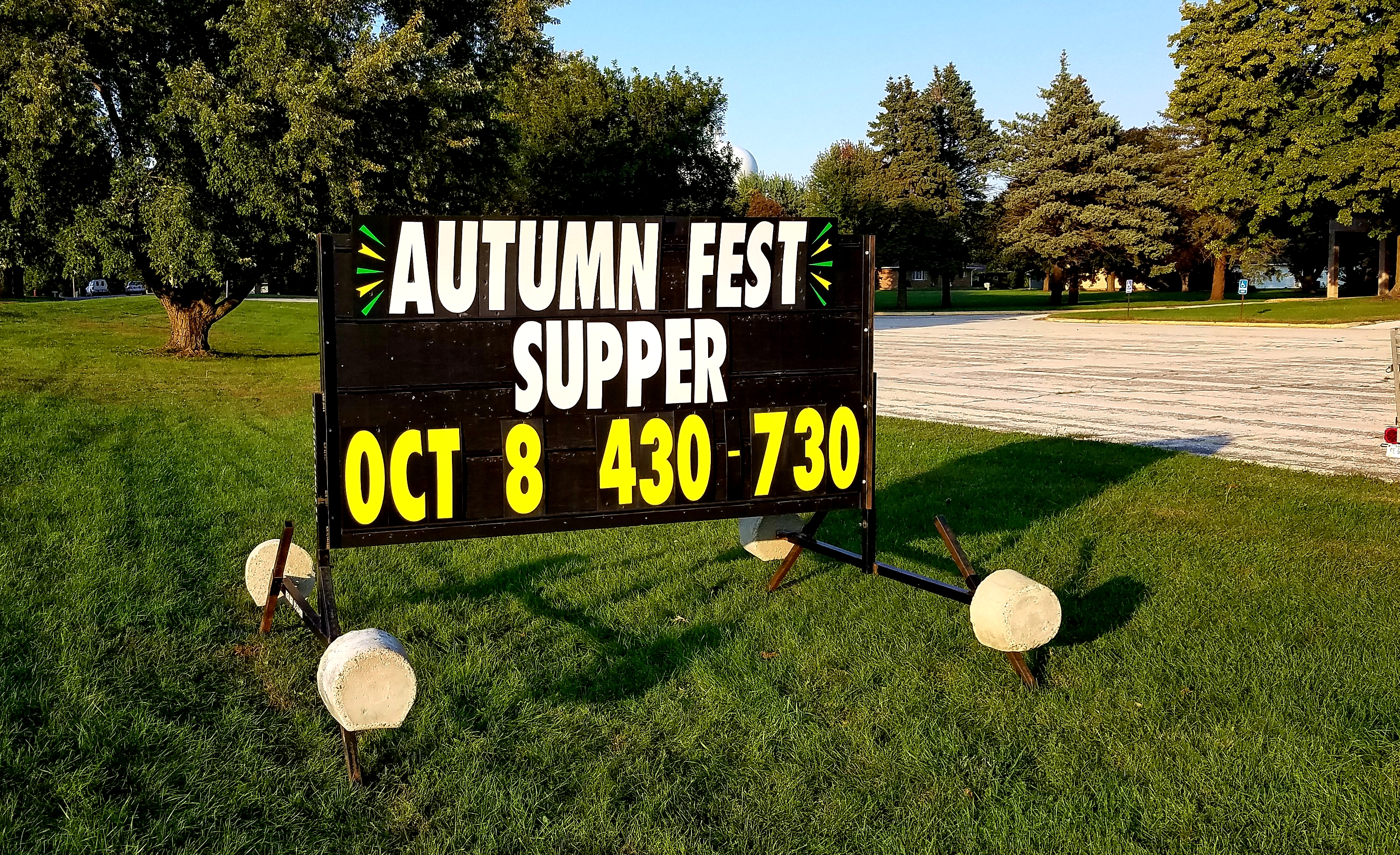 Black portable sign announcing an Autumn Fest supper